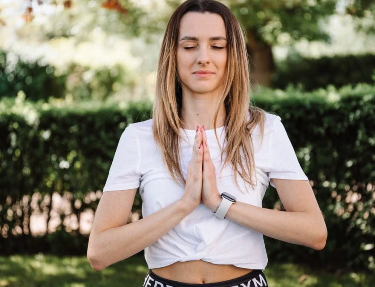 A serene moment of a woman practicing yoga with namaste pose outdoors, embracing mindfulness.